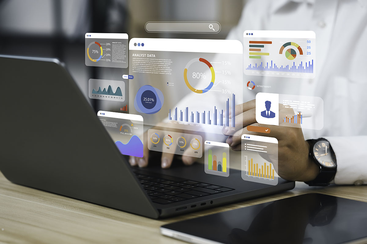 analyst uses laptop to examine demographic data with bar and pie chart graphs | Corporate Synergies