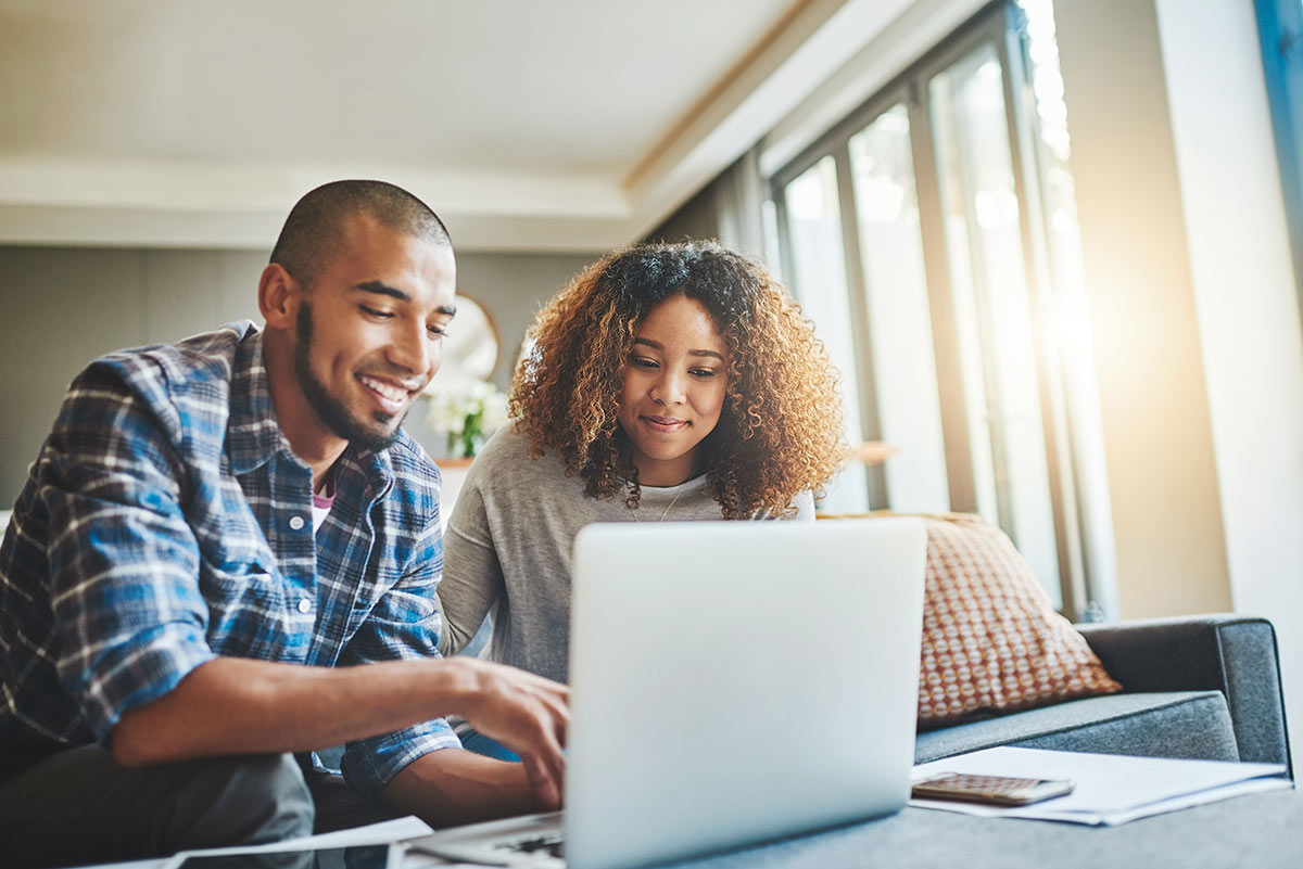 a couple reviews their new coverage on a laptop sitting in their living room |Corporate Synergies