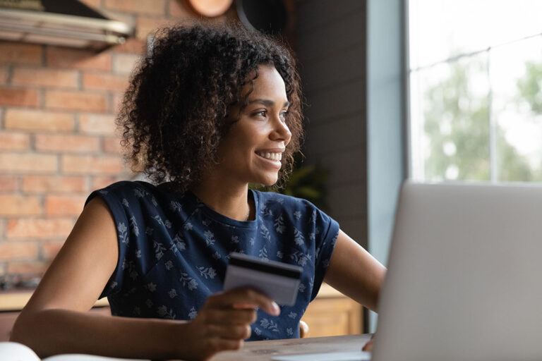 African-American woman holds bank card and contemplates financial wellbeing benefits at work |Corporate Synergies