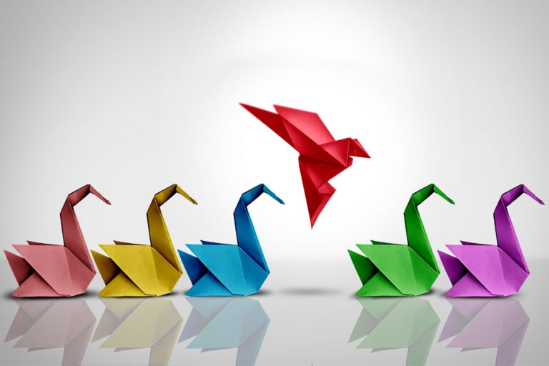 paper swans with bright red one flying to represent ICHRAs as radical |Corporate Synergies