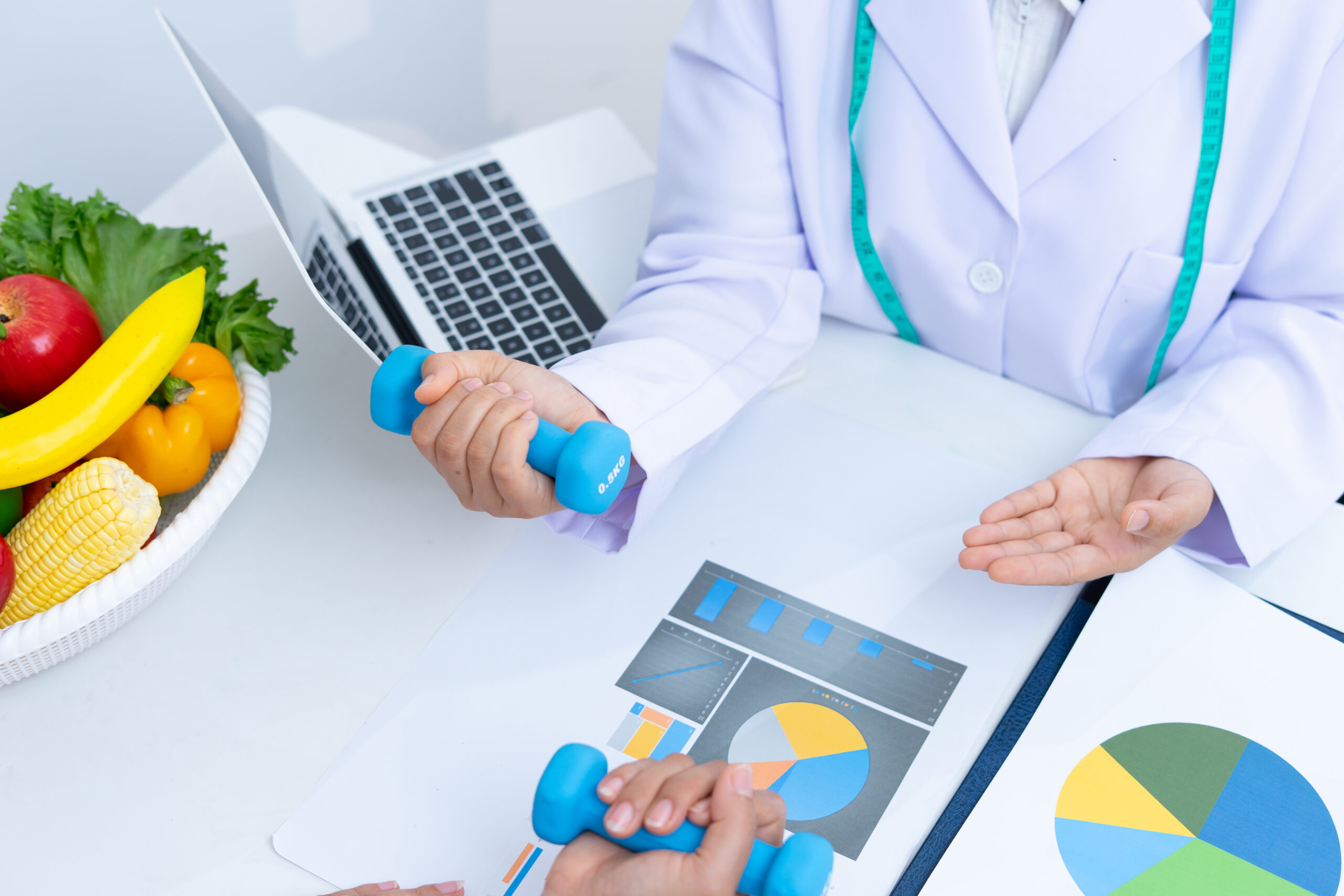 Doctor reviews metabolic health data with patient while demonstrating how to use dumbbells | Corporate Synergies