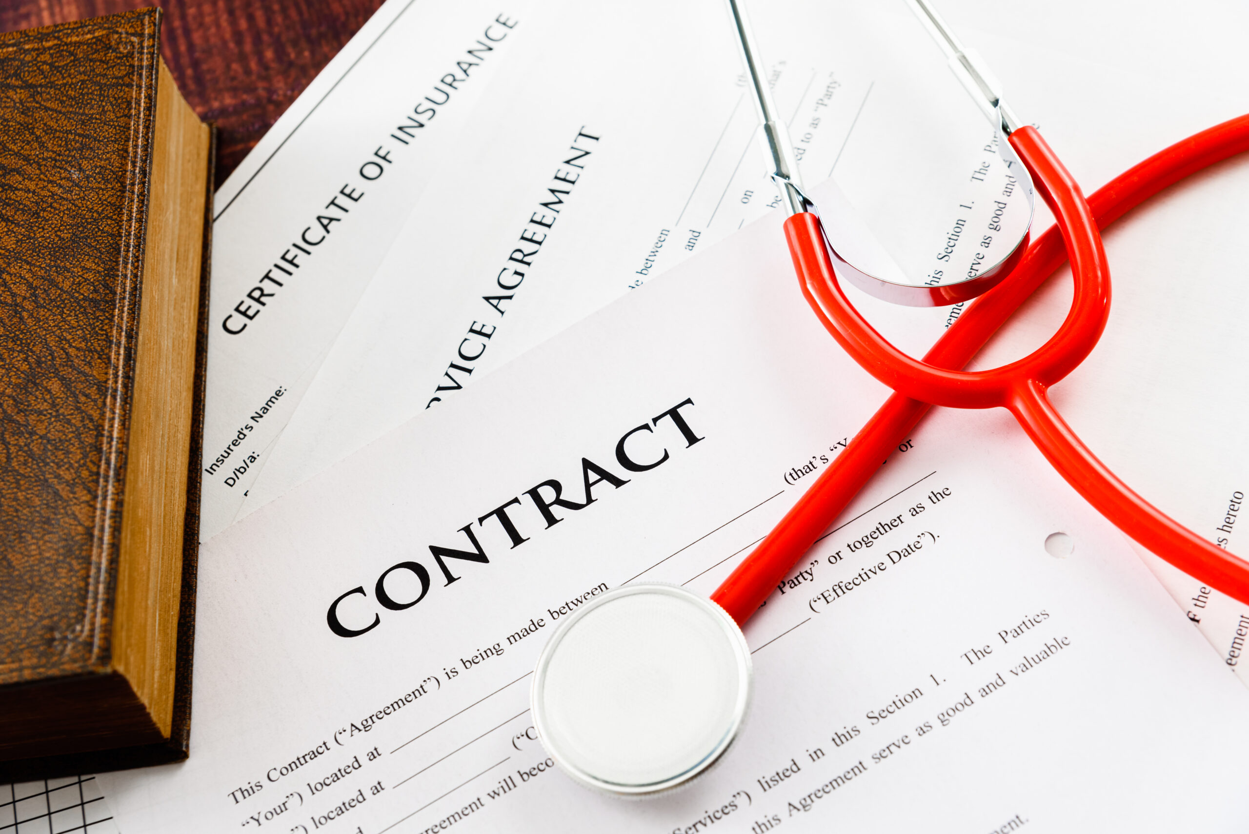 Unsigned health system contracts with stethoscope on top. |Corporate Synergies