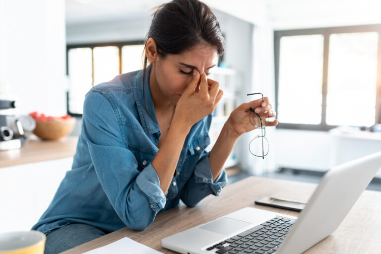 A stressed employee pinches her brow while reviewing her benefits illustrating the trust gap |Corporate Synergies